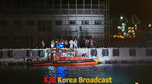 부두 구조물에 있는 해상추락자를 구조대가 구조하고 있다..png